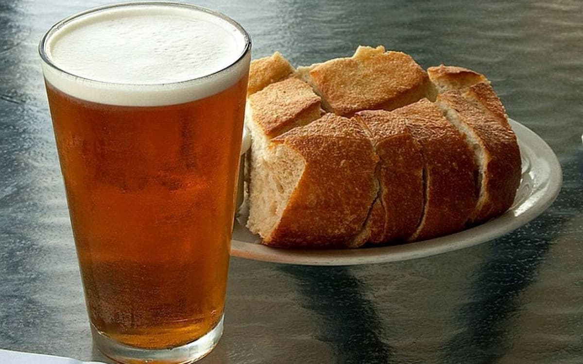 a pint of zero beer beside a plate of bread